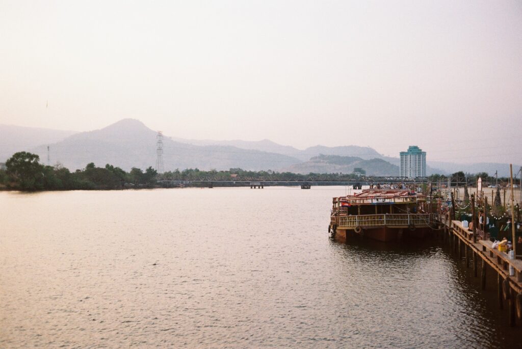 Boats on the Kampot River at dusk with mountains in the distance