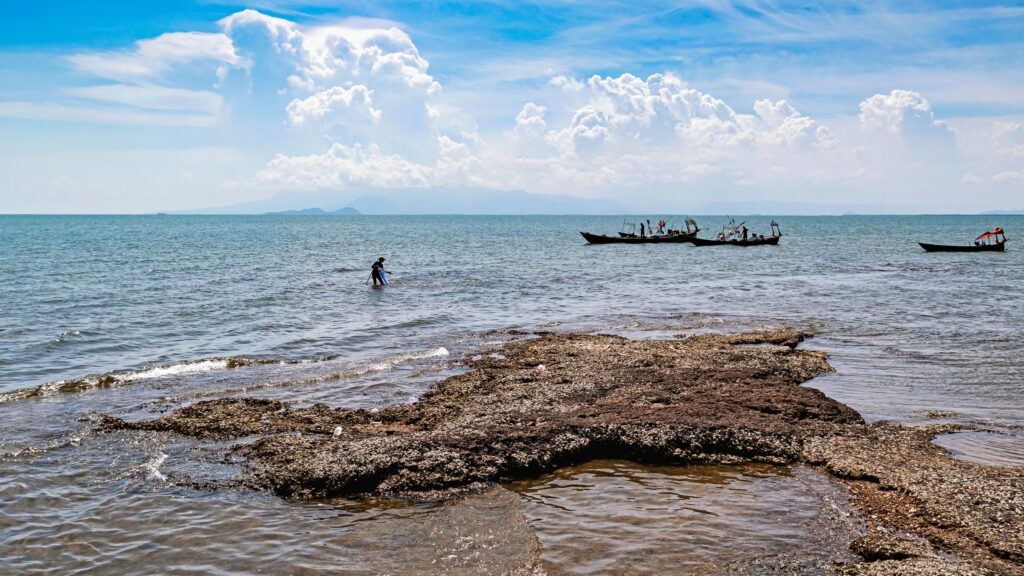 Boats resting near a rocky shore at Kep on the Cambodian coast under a cloudy sky