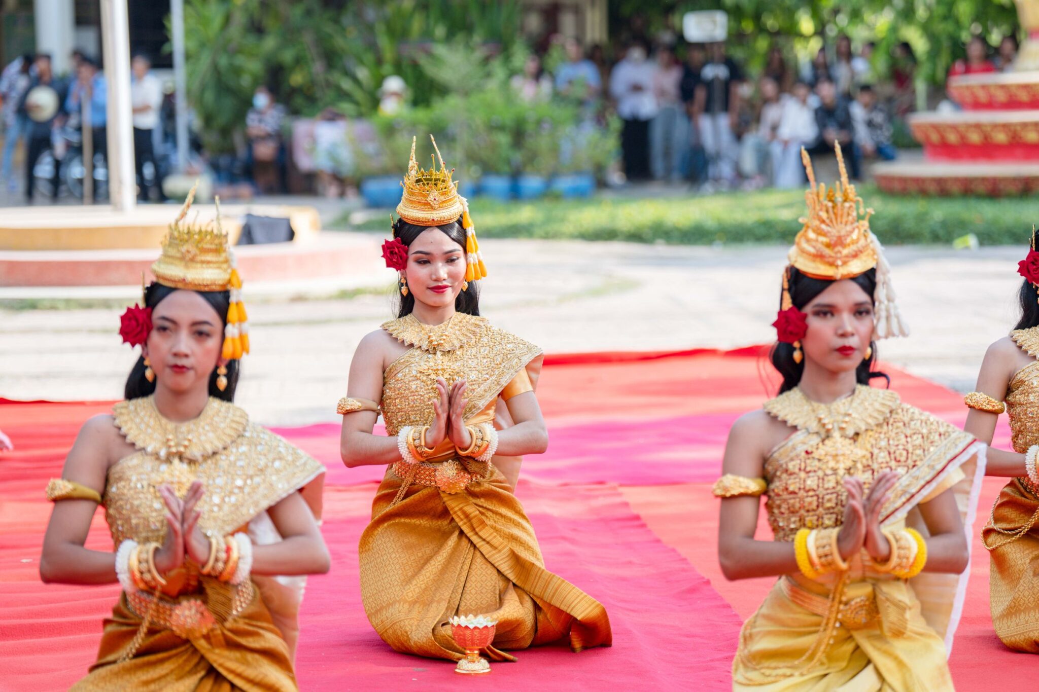 Women in traditional Khmer costume with gold headdresses kneeling in a dance performance in Battambang